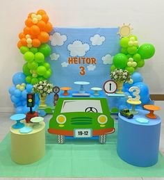 a green car parked in front of a table with balloons and decorations on it's sides