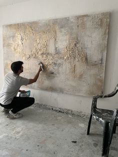 a man painting a large piece of art on the wall