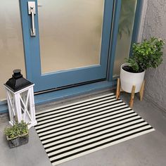 a black and white striped rug sitting next to a blue door with potted plants