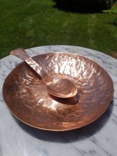 a large metal bowl sitting on top of a marble table with a spoon in it