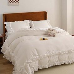 a bed with white ruffled sheets and pillows