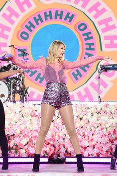 taylor swift performing on stage with her arms outstretched