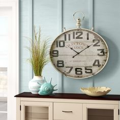 a clock on the wall next to a cabinet with vases and other items in it