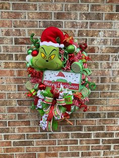 the grinch christmas wreath hanging on a brick wall