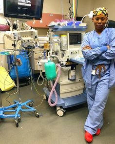 a woman in scrubs standing next to an operating room with medical equipment on the floor