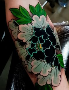 a woman's arm with a flower tattoo on it and green leaves in the center