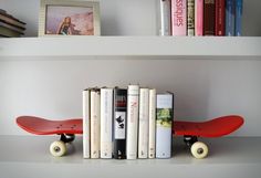 a book shelf with books and a skateboard on top of it, sitting next to a row of books