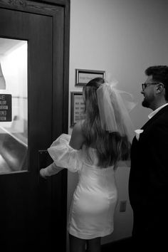 a man and woman are standing in front of an elevator with veils over their heads