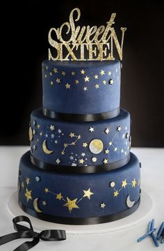 a three tiered blue cake with gold stars and moon decorations on the top layer