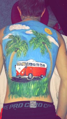 a man with his back painted to look like a bus driving down the road and palm trees