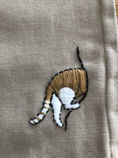 a cat embroidered onto the side of a jacket with gold and white stripes on it