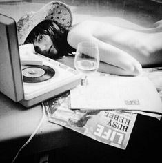 a woman laying on top of a table next to a record player and a glass of wine