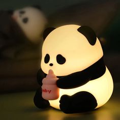 a panda bear sitting on top of a table next to a light that says i love you