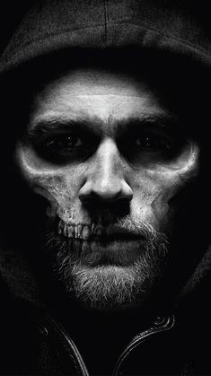 a black and white photo of a man wearing a hoodie with his face painted like a skull