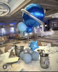 blue and silver balloons are on display in a room with white tablecloths, chairs and tables