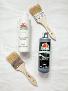 some paint and a brush sitting on a white sheet next to it's contents