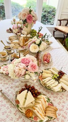 a table topped with plates filled with food and flowers on top of a white table cloth