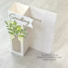 an open card with a plant in a vase on the inside, and a tag that says sending