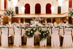 the tables are set up with white linens and greenery for an elegant wedding reception