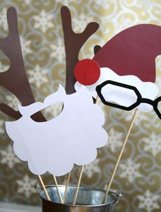 santa claus and reindeer paper masks on sticks in a cup with snowflakes behind them