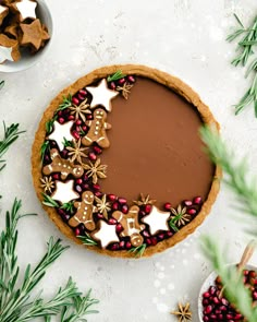 a chocolate tart decorated with gingerbread stars and christmas decorations on a white table