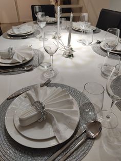 the table is set with silver and white plates, silverware, and napkins