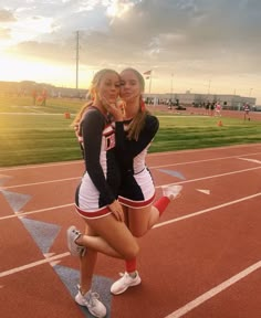 two cheerleaders pose for a photo on the track