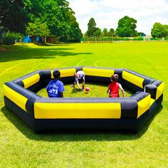 two children playing in an inflatable ball pit on the grass with trees in the background