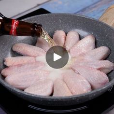 raw chicken being cooked in a frying pan with a bottle of beer on the side