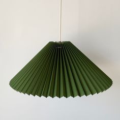 a green paper fan hanging from a white wall