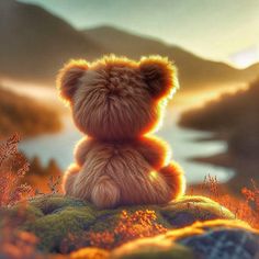 a brown teddy bear sitting on top of a lush green field next to a lake