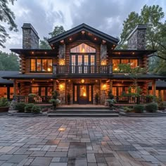 a large log home lit up at night with lights on the front porch and windows