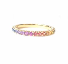 a yellow gold ring with rainbow colored stones on the inside and outside, set against a white background