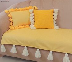 a couch with yellow pillows and tassels on it