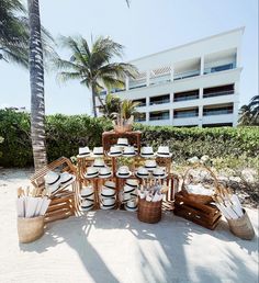 the table is set up on the beach with plates and utensils in baskets