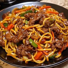 a black plate topped with beef and noodles