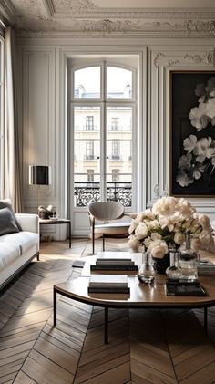 a living room filled with furniture and flowers on top of a coffee table in front of a window