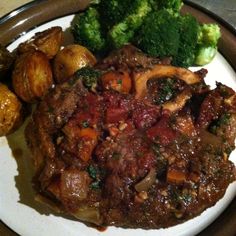 a white plate topped with meat, potatoes and broccoli