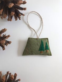 an ornament hanging from the side of a pine tree with two small trees on it