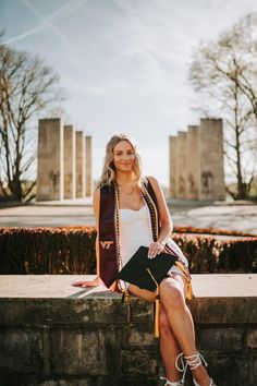 a woman is sitting on a wall with her legs crossed and looking at the camera