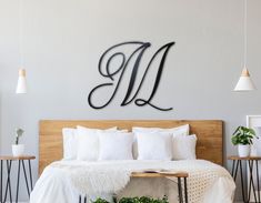 a monogrammed wall mounted above a bed in a bedroom with white sheets and pillows