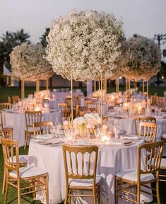 an outdoor dining area with tables, chairs and centerpieces covered in white flowers