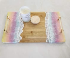 a wooden tray topped with a candle next to a small cup on top of it