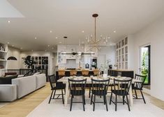 a dining room and living room combination in an open floor plan with white walls, wood floors, and black chairs