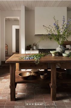 a wooden table topped with bowls and vases filled with flowers on top of it