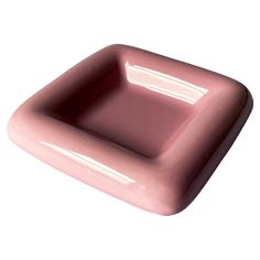 a pink square shaped object sitting on top of a white surface