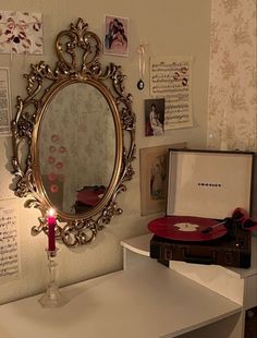 a mirror sitting on top of a white table next to a red box with a candle in it