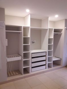 an empty room with white shelves and drawers