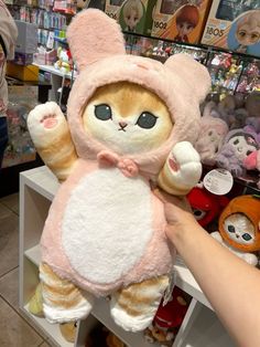 a person holding a stuffed animal in front of shelves filled with other plush toy animals