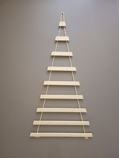 a wooden christmas tree hanging on a wall in a room with grey walls and flooring